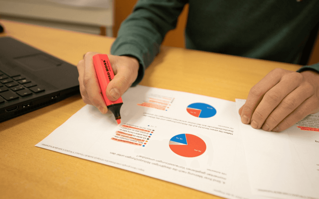 Marketing professional analyzing data charts with a highlighter, indicative of Search Engine Marketing Reporting Software analytics review.