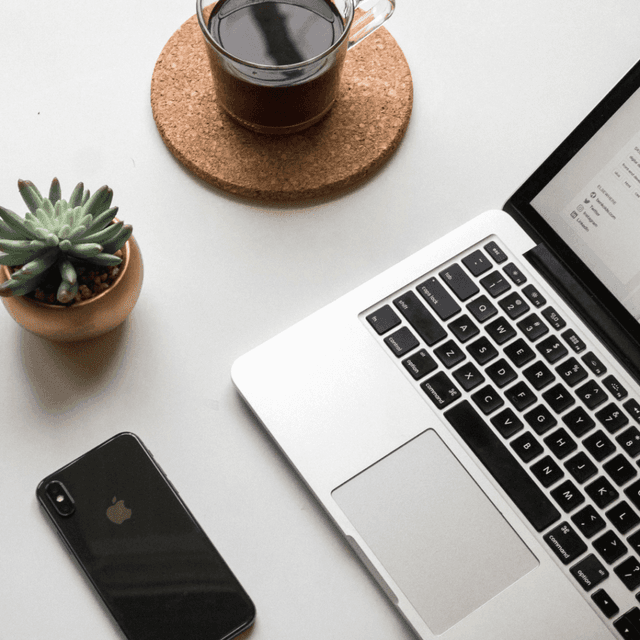 A neatly organized desk with a laptop open to a Website Optimization Report, accompanied by a smartphone, a potted succulent, and a cup of coffee, symbolizing a productive and focused work setting for website analysis.