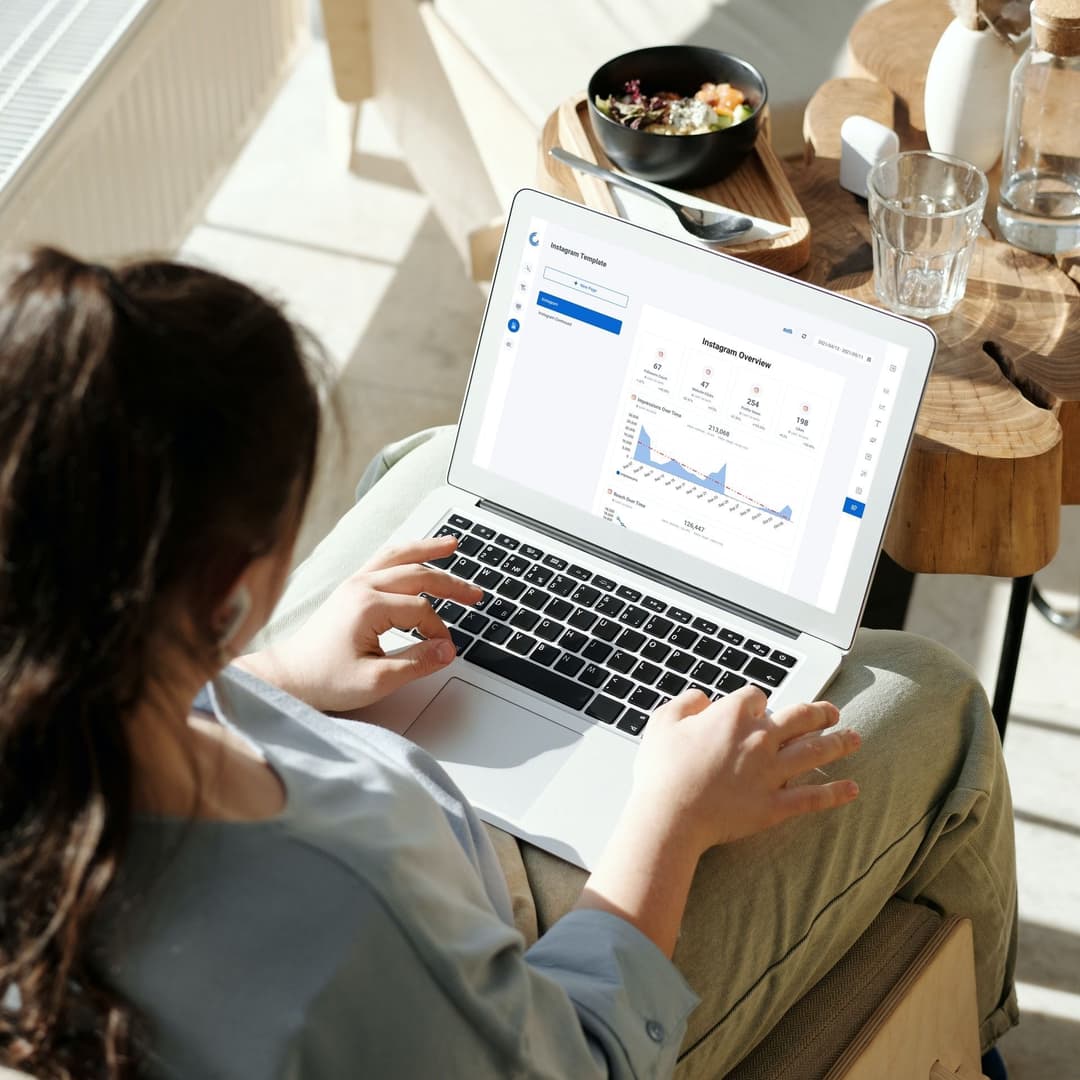 Professional analyzing automated marketing reports on a laptop, showcasing graphs and key digital marketing metrics.