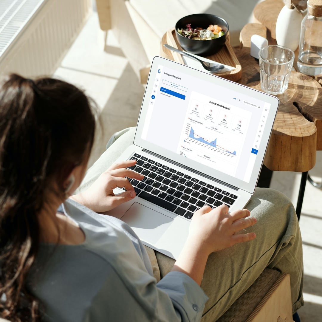 Professional analyzing automated marketing reports on a laptop, showcasing graphs and key digital marketing metrics.