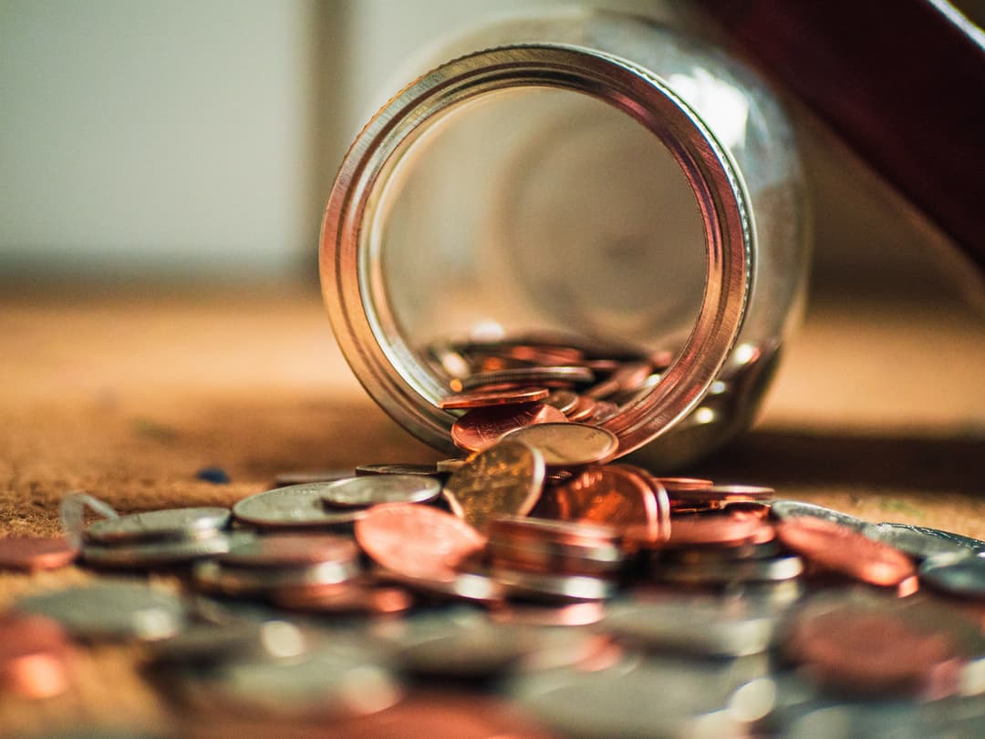An image of a jar of coins spilled on the table.