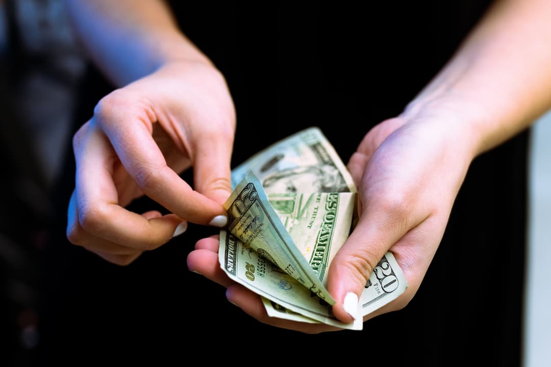 An image of a hand countring dollar bills.