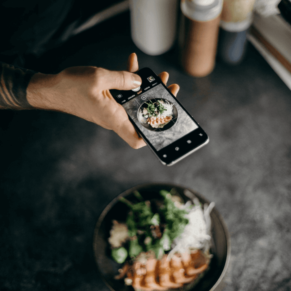 "Smartphone capturing a photo of a healthy meal, an activity often reflected in the content analysis of an Instagram Insights Report."