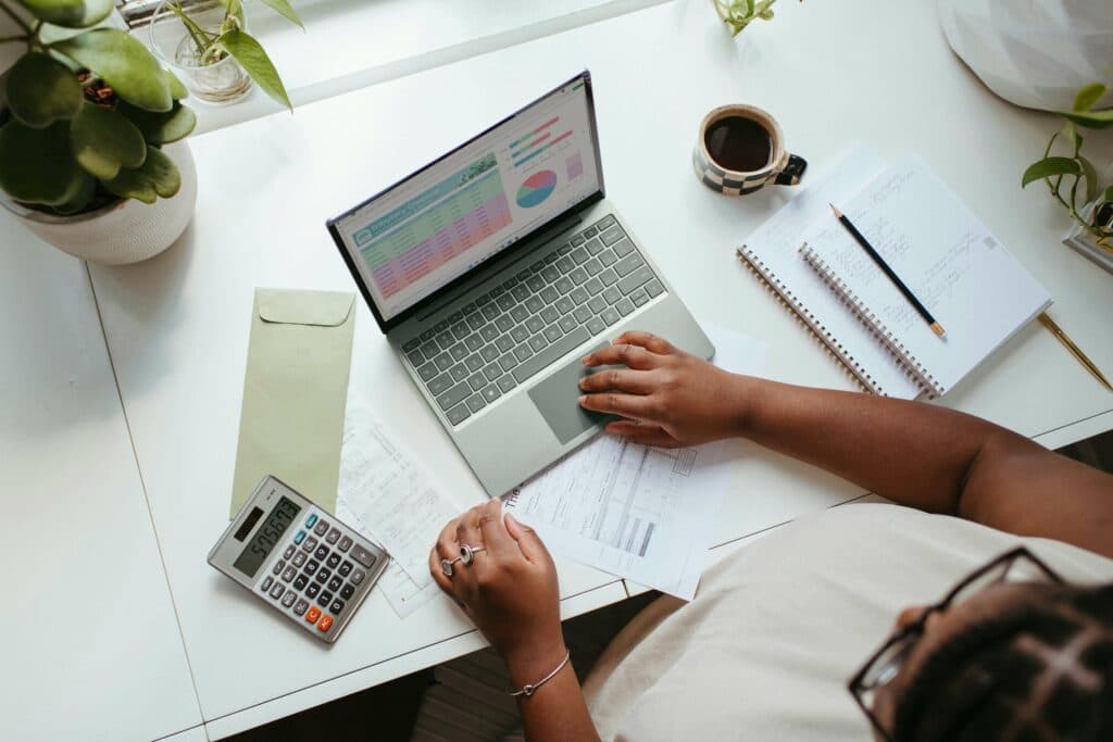 Person working on a laptop with charts and data analysis, representing how free AI tools assist digital marketing agencies in tracking campaign performance and optimizing strategies.