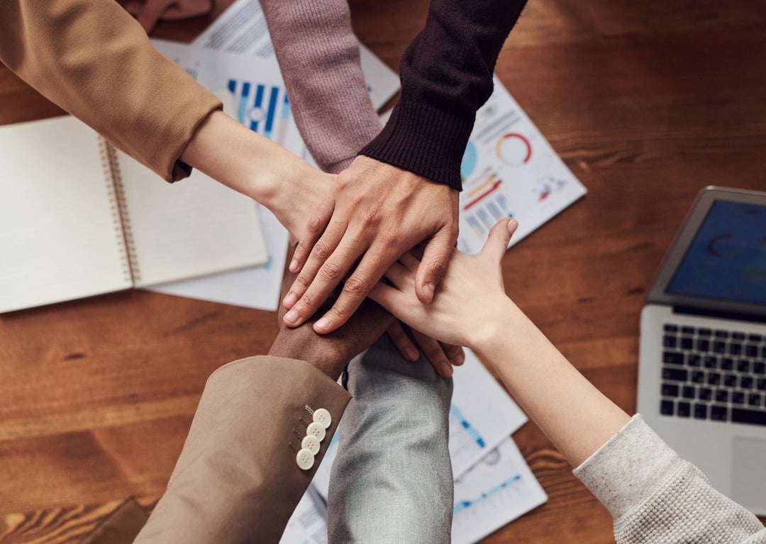 Image of people placing hands on eachothers