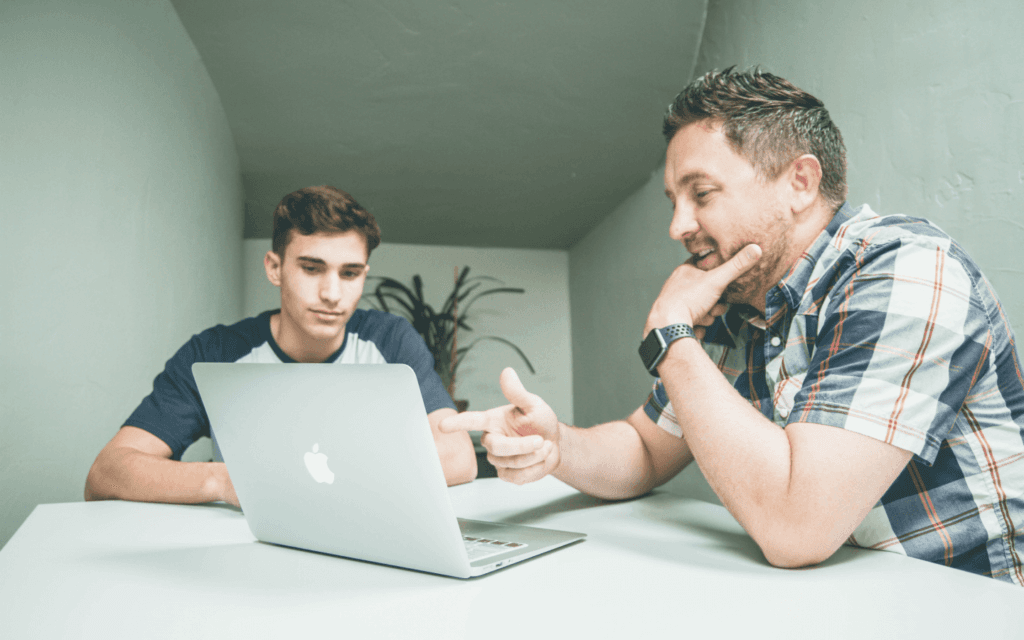 Two individuals discussing over a laptop, possibly exchanging ideas about digital marketing innovations in a cooperative work environment.