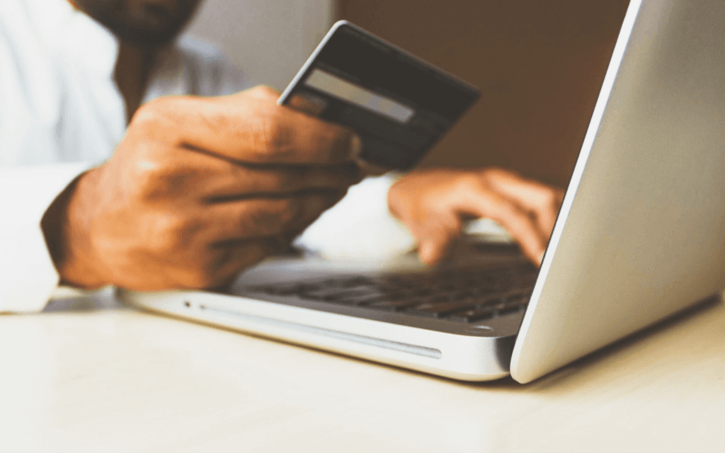 Person using a credit card on a laptop, symbolizing "client retention" in the e-commerce sector.
