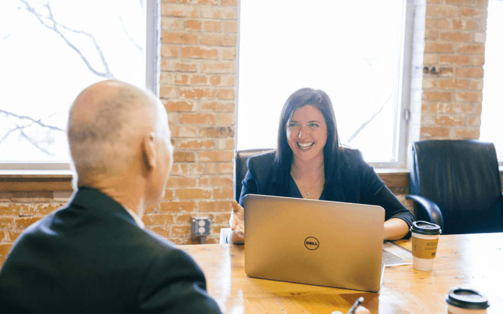 Businesswoman and colleague discussing an Ideal Customer Profile in a bright office space, conveying teamwork and customer-focused strategy.