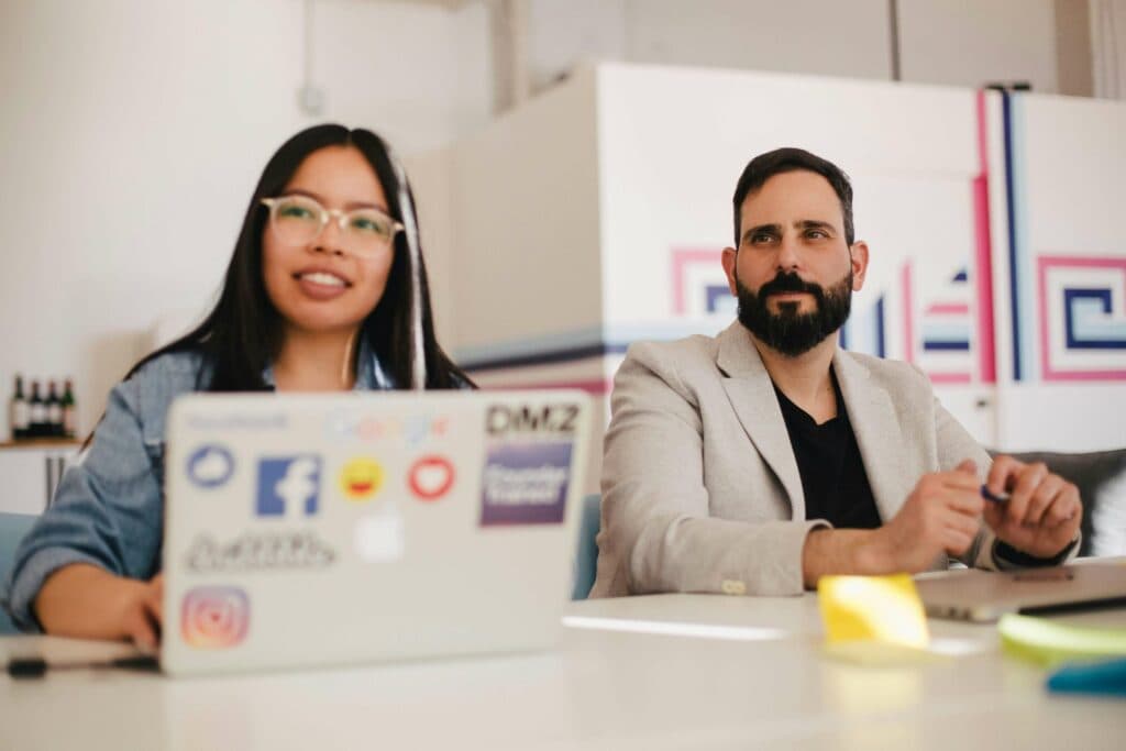 Two professionals in a meeting with laptops, representing collaboration and the use of free AI tools in digital marketing agencies for optimized campaign strategies.