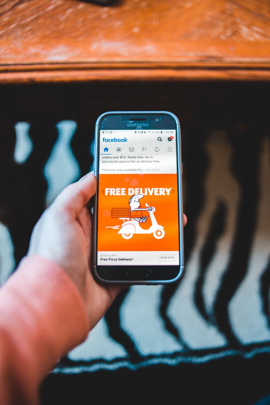 Person holding a Samsung phone with a Facebook ad for "Free Delivery," exemplifying successful "Paid Advertising in Digital Marketing" tactics.