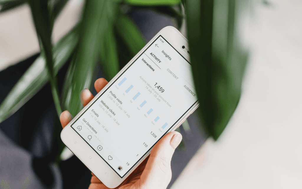 Hand holding a smartphone displaying digital marketing analytics, emphasizing the impact of digital marketing innovations on strategy optimization.