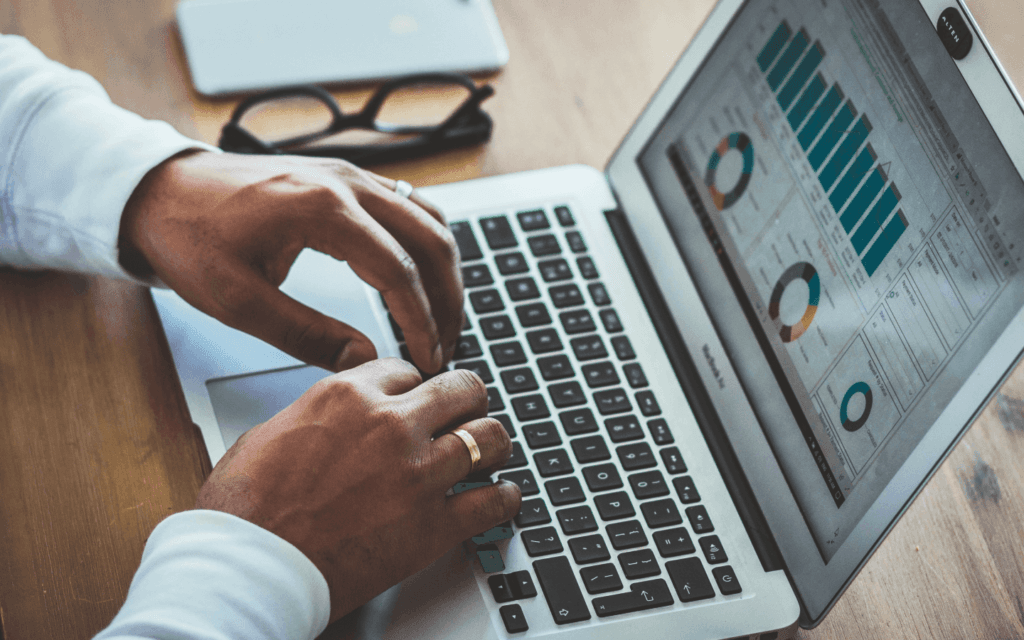 Professional examining data analytics on a laptop, a key component of Digital Agency Workflow, with performance charts and metrics visible on the screen.