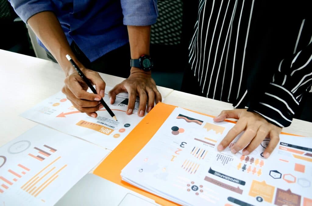 Two individuals analyzing marketing data and performance charts, representing the use of AI tools for marketing to optimize campaigns and track metrics.