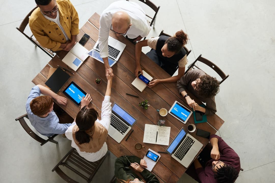 People sitting around a table shaking hands