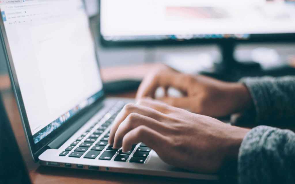 "Professional working on a laptop, potentially drafting an Instagram Insights Report to strategize social media growth."