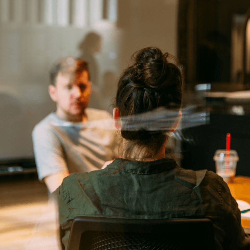 Two professionals in a candid conversation, possibly strategizing about influencer marketing, in a casual office setting with a focus on interpersonal communication.