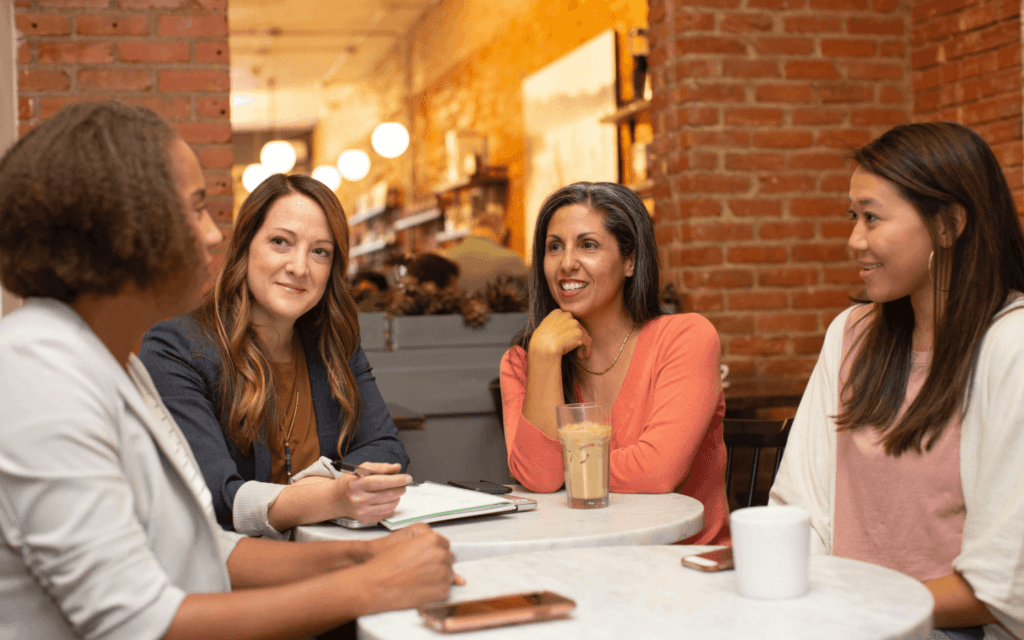 Four professionals in a collaborative meeting at a cafe, exemplifying client retention through strong relationship building.