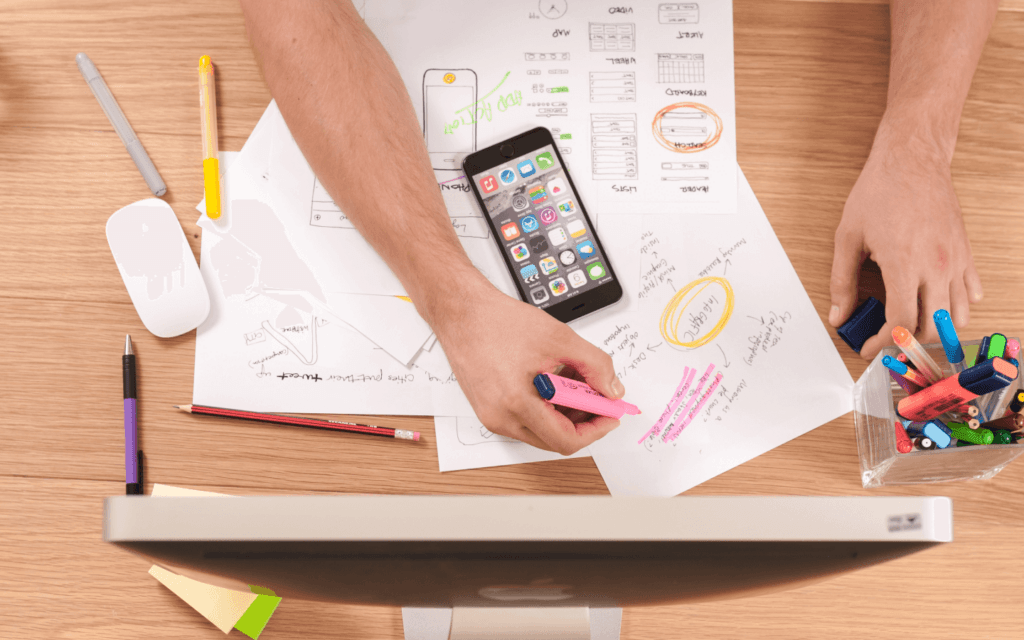 Hands highlighting key points on a document for a Keyword Research Report, with a smartphone and office supplies on the desk.