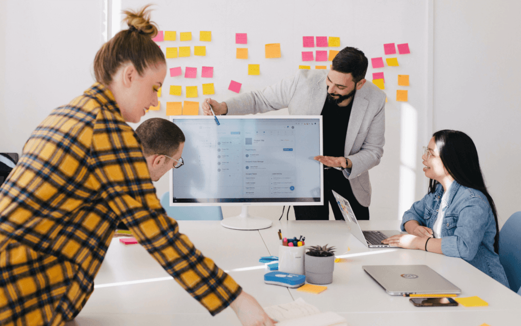 A collaborative team meeting where professionals are discussing the Blended Query Builder by Oviond, focusing on its enhanced features and the addition of new data sources, in a well-organized office setting.