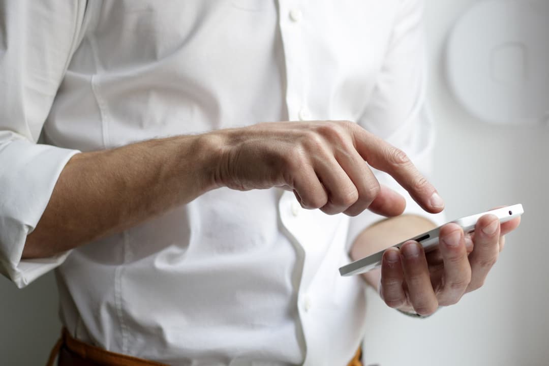 A guy scrolling through a white phone.