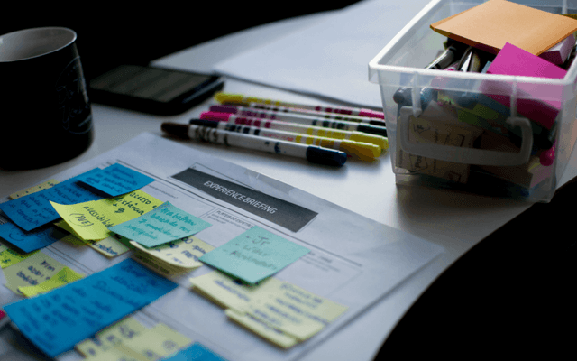 A strategic marketing workspace with post-it notes, markers, and briefing papers, showcasing the use of Marketing Management Tools.