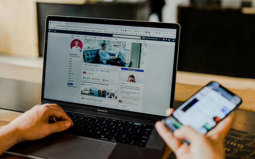 Social media management in action with a Facebook page open on a laptop and a smartphone, demonstrating the creation of a social media analytics report PDF.