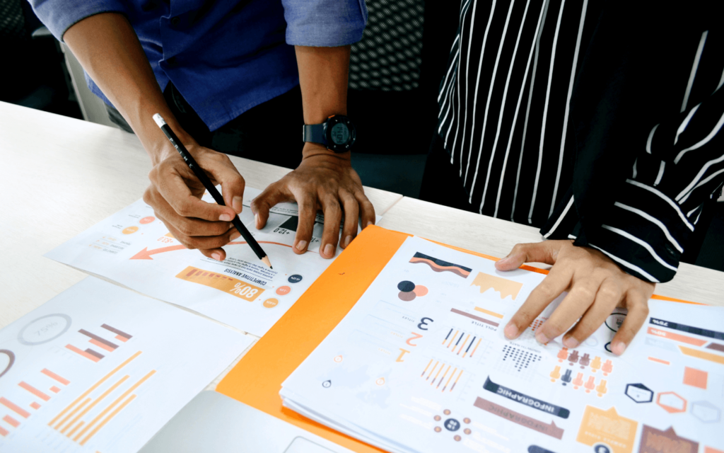 Close-up of professionals analyzing a PPC report template with colorful graphs and performance metrics on a paper, highlighting the importance of data in digital marketing.