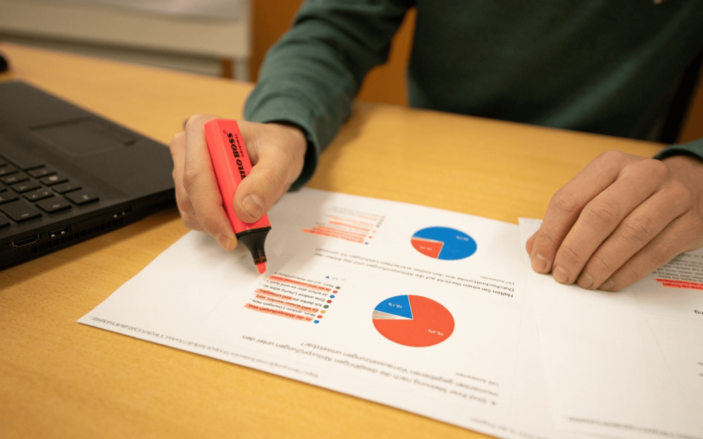 Marketing professional analyzing data charts with a highlighter, indicative of Search Engine Marketing Reporting Software analytics review.