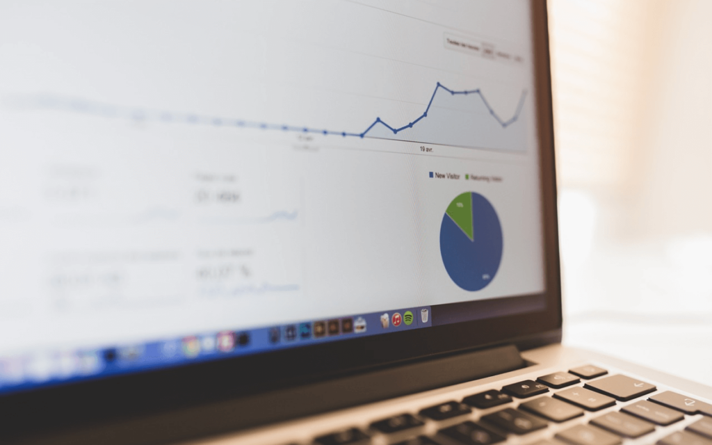 Close-up of a laptop screen displaying a line graph and pie chart, representing the analytical data of an All in One Digital Marketing Platform.