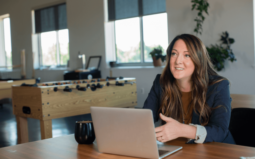 Businesswoman in a modern workspace discussing email marketing performance metrics, highlighting strategies for campaign optimization and metric analysis on her laptop.