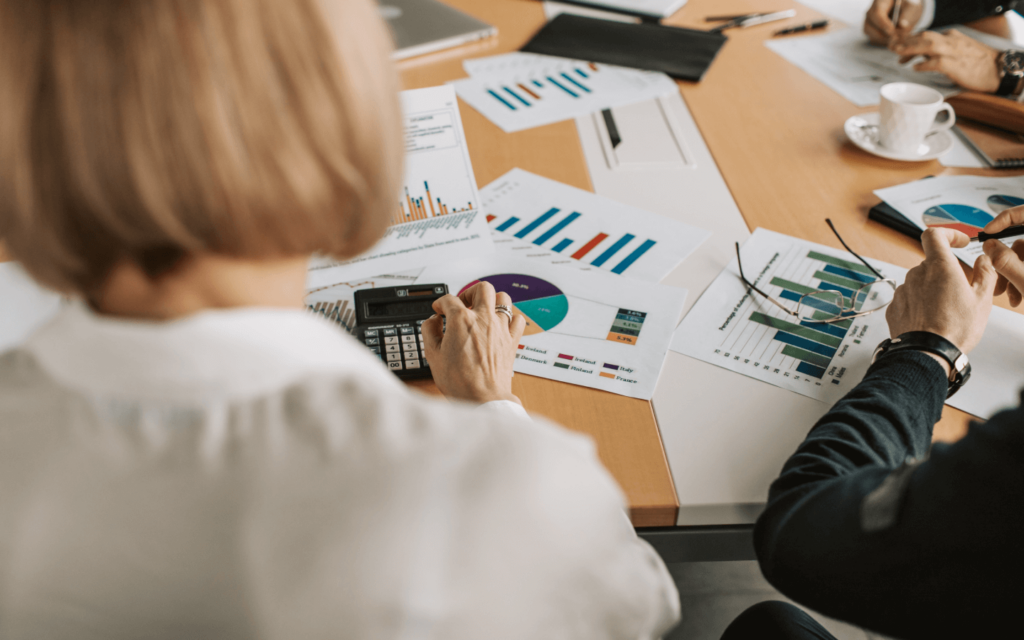 Business professional calculating statistics surrounded by colorful data charts, embodying 'Reporting Best Practices'.