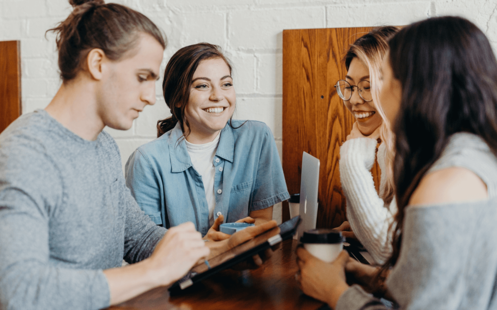 Young professionals in a team meeting, engaged in a lively discussion about reporting best practices with digital devices and coffee on the table.