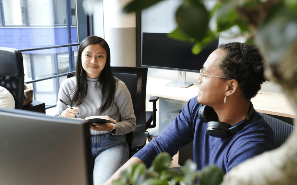 Two digital marketing professionals collaborating in an office, highlighting teamwork and communication as key elements in developing successful digital marketing strategies.