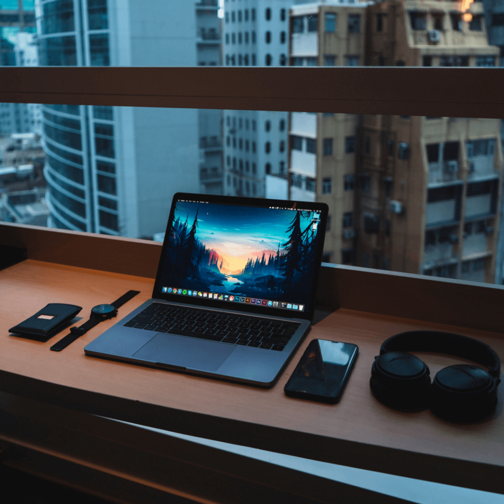 Contemporary digital marketing setup featuring a laptop with a vivid screen, headphones, and smartphone, all overlooking a city view, illustrating a dynamic and connected digital marketing environment.