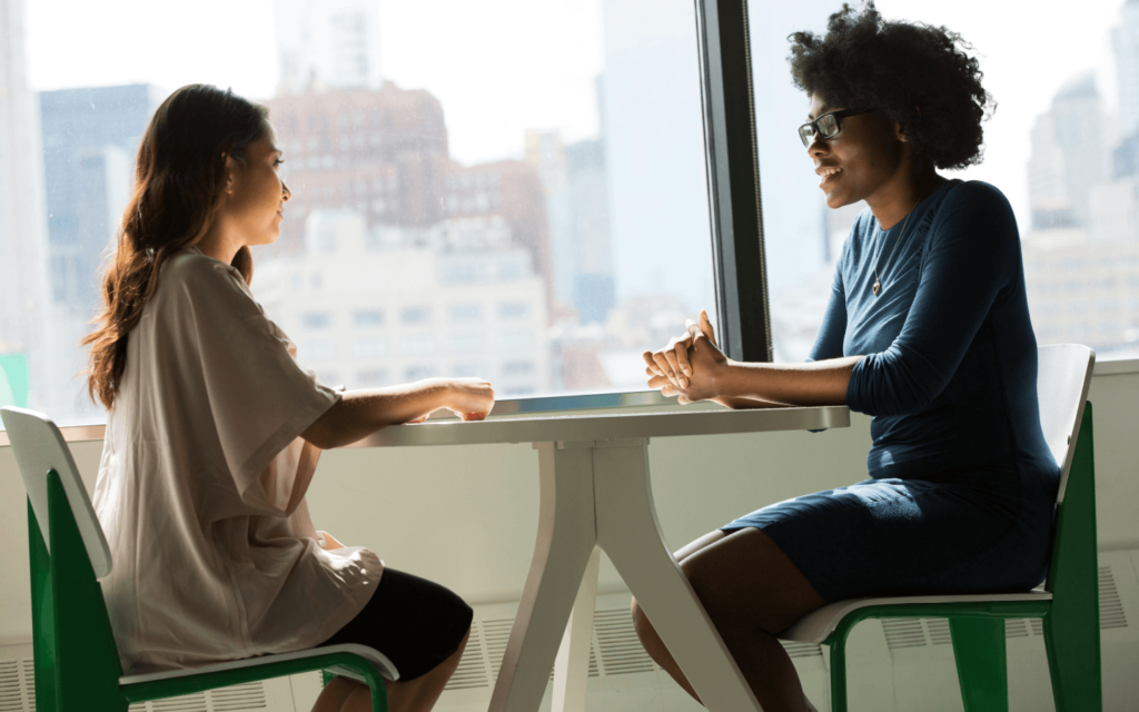 Two professionals in a discussion at a table with a city view, possibly strategizing about influencer marketing.