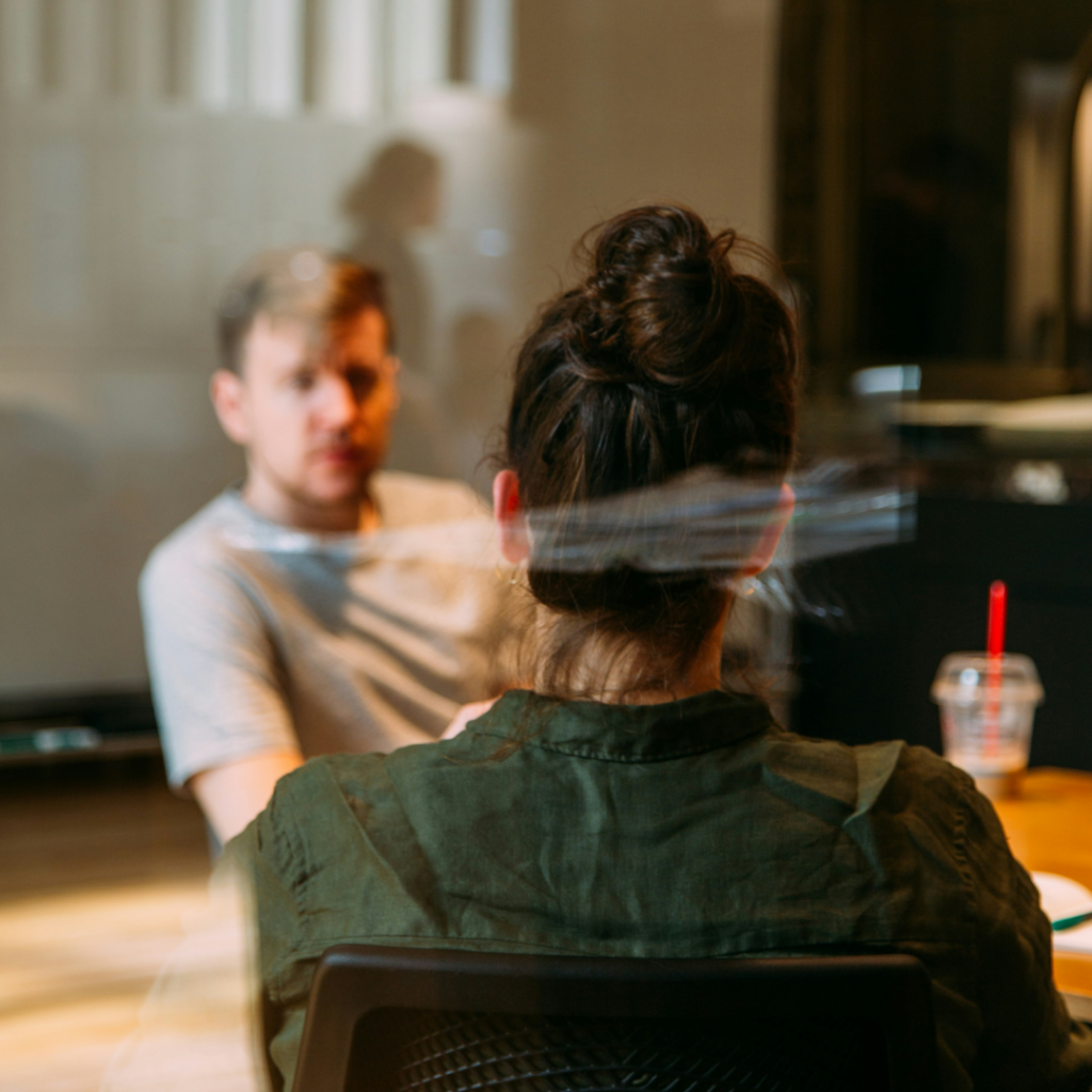 Two professionals in a candid conversation, possibly strategizing about influencer marketing, in a casual office setting with a focus on interpersonal communication.