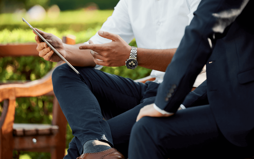 Two professionals in an outdoor setting discussing strategies, with one pointing to a tablet screen, indicative of an 'Affiliate Marketing for Beginners' scenario.