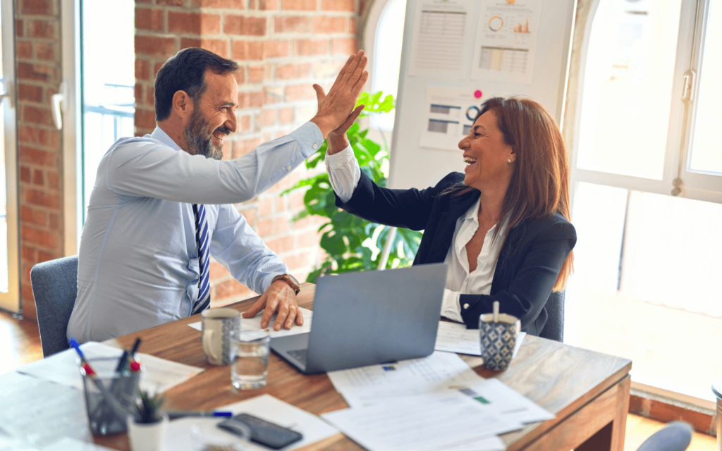 Two smiling professionals celebrating with a high-five in an office, representing a successful venture in 'Affiliate Marketing for Beginners'.