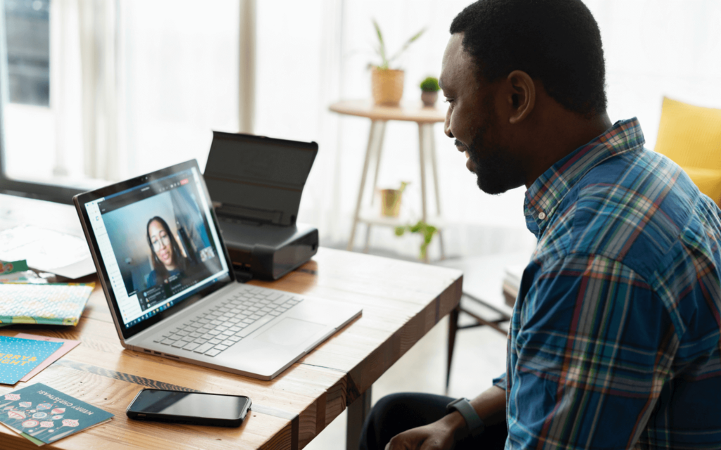 Man in a home office on a video call with a female mentor, indicative of an 'Affiliate Marketing for Beginners' online coaching session.