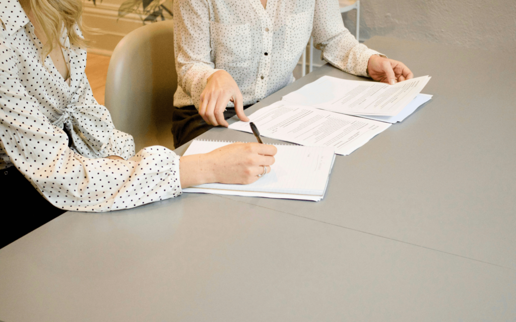 Two professionals evaluating marketing strategies, with one person writing notes, highlighting the strategic planning phase in a business setting.