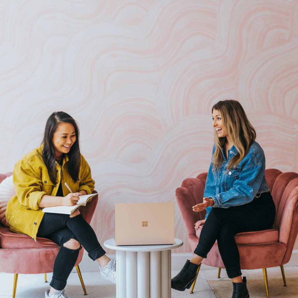 Two individuals in a vibrant and informal setting engaging in a lively discussion with a laptop open, potentially displaying client reporting software for collaborative strategy planning.