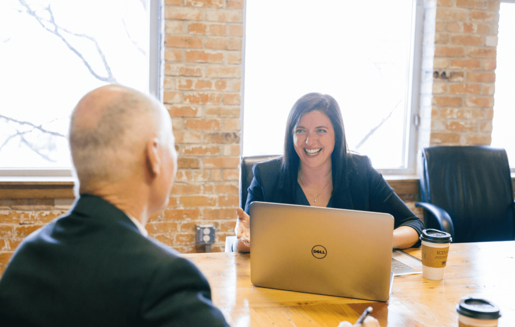 SEO professional presenting a 'White Label SEO Reporting Dashboard' on a laptop to a client in a modern office setting with a rustic aesthetic.