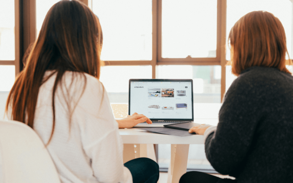 Two colleagues working together on a laptop in a well-lit office space, possibly creating or analyzing lead magnets for marketing campaigns.