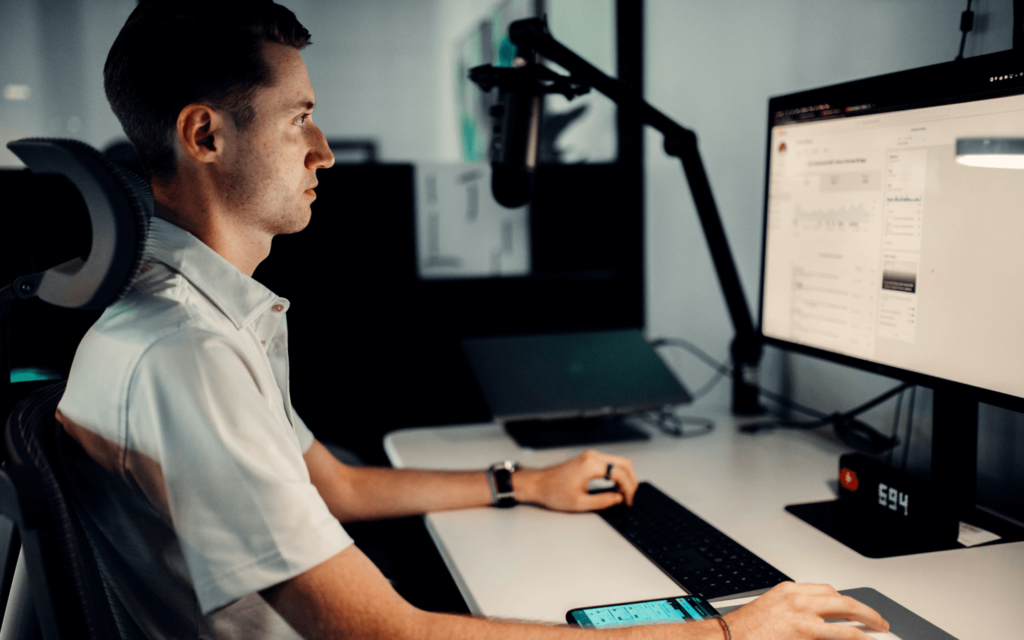 A man analyzing GA 4 reports on a desktop monitor in a modern office setting, reflecting the importance of data-driven decision-making.