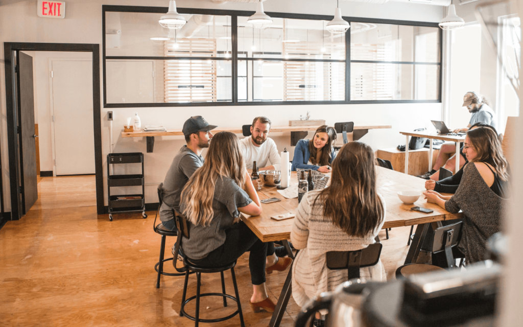 A group of colleagues collaborating at a wooden table in a bright office space, potentially discussing GA 4 reports, showcasing teamwork and communication.